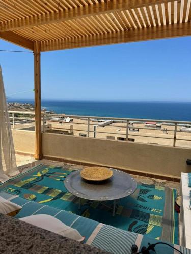 a view of the beach from a balcony with a table at Location d'un appartement in Tizouiar