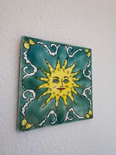 a tile with a drawing of a sun on a wall at Location d'un appartement in Tizouiar