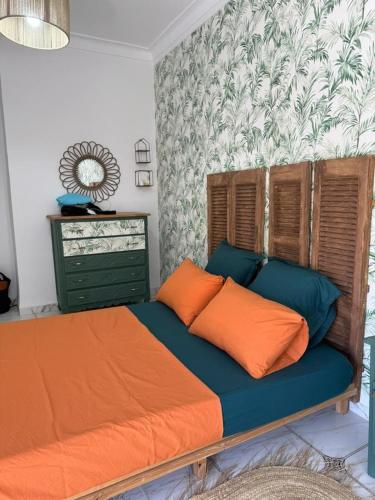 a bed with orange and blue pillows in a bedroom at Location d'un appartement in Tizouiar