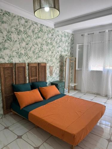 a bedroom with a large bed with orange pillows at Location d'un appartement in Tizouiar