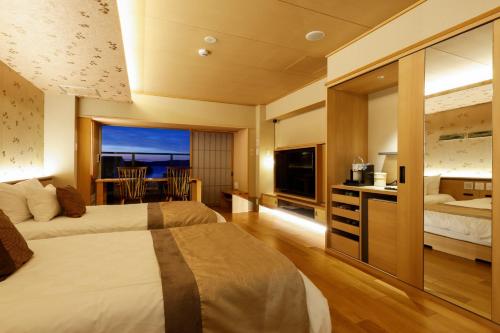 a hotel room with two beds and a television at Sun Urashima Yuki no Sato in Toba