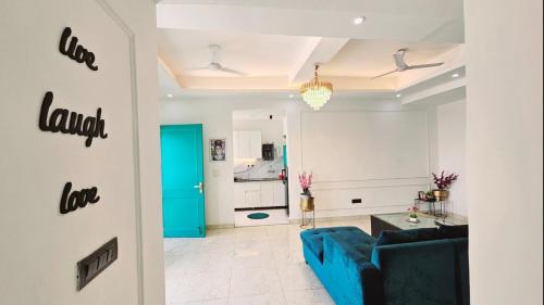 a living room with a blue couch and a kitchen at Mykonos Sky Penthouse Rooftop Pool 150" Cinema in Gurgaon