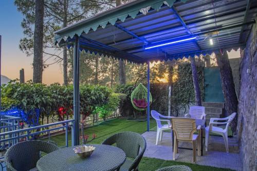 a patio with a table and chairs and a blue light at Exotic Stays I Pine Group Of Hotels & Villas Kasauli in Kasauli