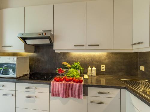 a kitchen with white cabinets and tomatoes on a counter at House in Zingem near Hiking Trails in Zingem