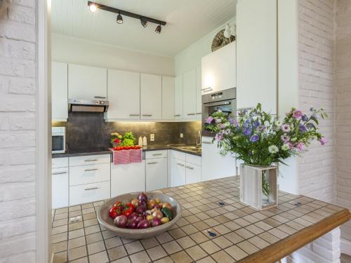 a kitchen with a bowl of fruit and a vase of flowers at House in Zingem near Hiking Trails in Zingem