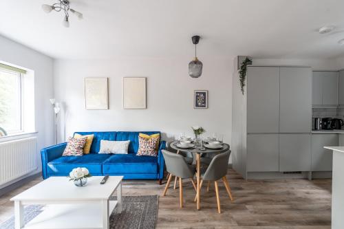 ein Wohnzimmer mit einem blauen Sofa und einem Tisch in der Unterkunft 4Beds Contractor and Family Haven near Pinewood and Warner Bro studios in Chalfont Saint Peter