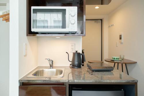 東京にあるThe underz suite residence Ikebukuroのシンクと電子レンジ付きのキッチン