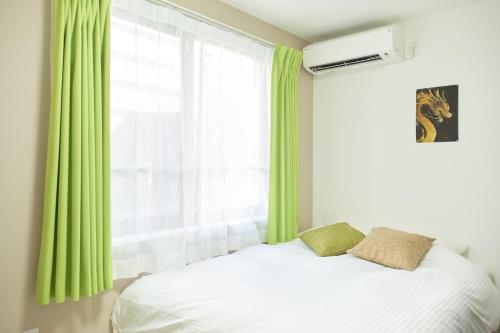 東京にあるThe underz suite residence Ikebukuroのベッドルーム1室(緑のカーテンと窓付きのベッド1台付)