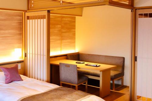 a hotel room with a desk and a bed at Sun Urashima Yuki no Sato in Toba