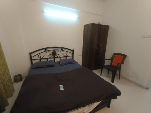 a bedroom with a black bed and a chair at Sky line villa, Lonavla in Lonavala