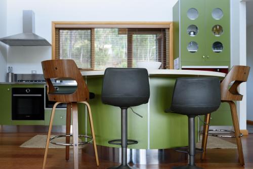a kitchen with three bar stools in front of a counter at Scenic Getaway with Breathtaking Water Views in Gordon