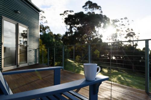 a coffee cup sitting on a blue bench on a deck at Scenic Getaway with Breathtaking Water Views in Gordon