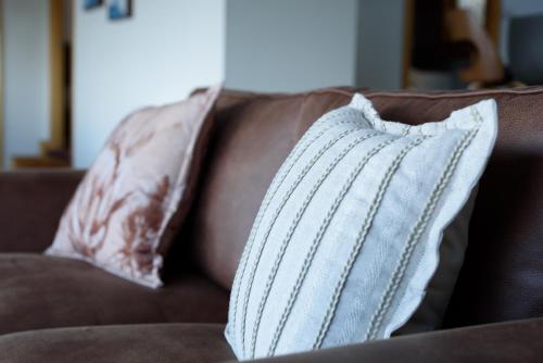 a white pillow sitting on a brown couch at Scenic Getaway with Breathtaking Water Views in Gordon