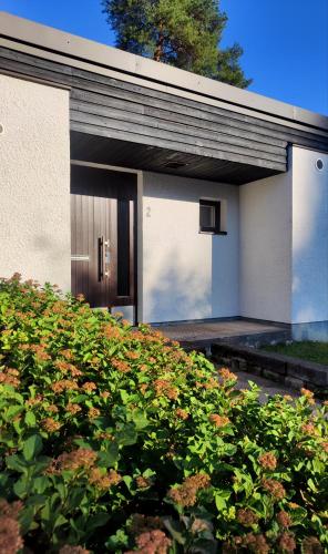 a white house with a brown door and some bushes at Honkatilat majoitus as 2 in Kajaani