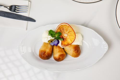two rolls on a white plate with an orange slice at R.HOTEL in Chernivtsi