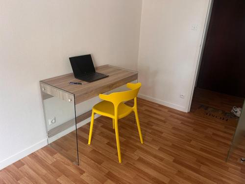 a yellow chair sitting next to a desk with a laptop at Trank'il appart in Marmande