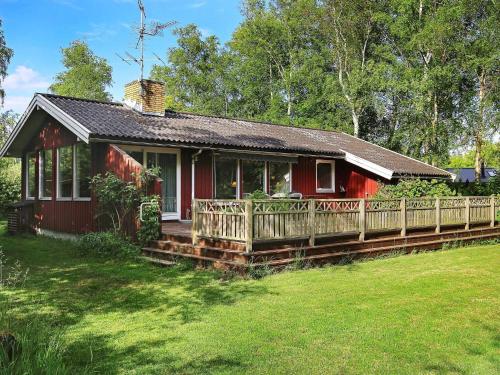 a red house with a porch and a yard at 4 person holiday home in Vejby in Vejby