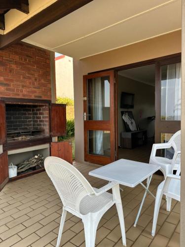 a patio with a table and chairs and a fireplace at BlueHive guesthouse Leisure in Port Edward
