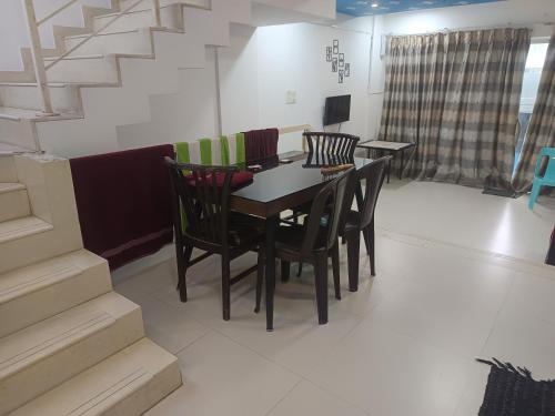a dining room with a table and chairs and stairs at Sky line villa, Lonavla in Lonavala