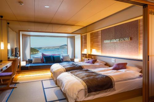 two beds in a room with a large window at Sun Urashima Yuki no Sato in Toba