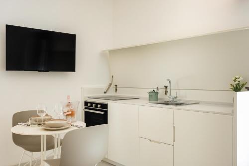 a kitchen with white cabinets and a table and a tv at Anita Rooms in Olbia