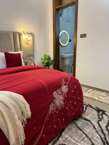 a bedroom with a red bed and a bathroom at DnJ cozy homes in Dar es Salaam