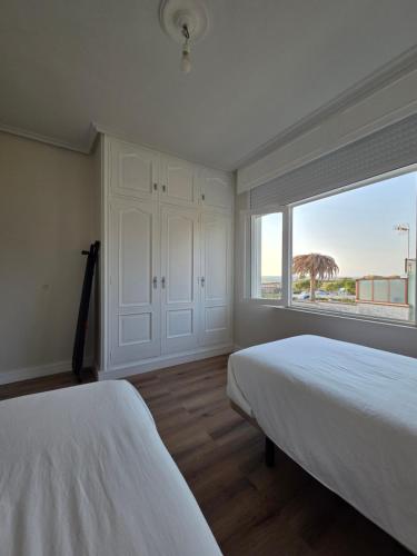 a bedroom with two beds and a large window at Casa frente al mar in Valdoviño