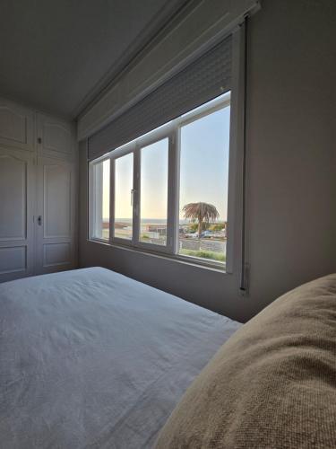 a bedroom with a large window with a view of the beach at Casa frente al mar in Valdoviño