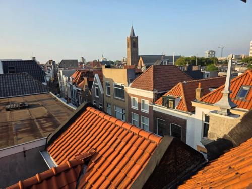 a view of roofs of buildings with a clock tower at Historic Canal-Side Apartment in Schiedam