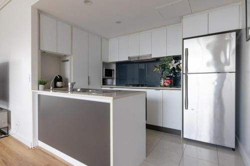 a kitchen with white cabinets and a refrigerator at Luxury Apartment Brisbane CBD in Brisbane