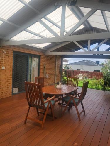 a patio with a wooden table and chairs on a deck at Venus Place 1 in Sydenham