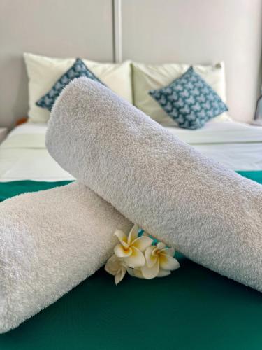 Una toalla enrollada sobre una cama con flores. en Tikaban, en Pointe d'Esny