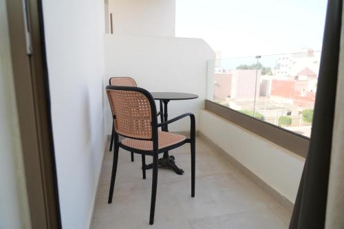 two chairs and a table in a room with a window at Hôtel Everest, Séjour Balnéaire à Saïdia in Saidia 