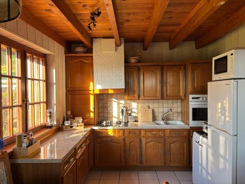 Una cocina con gabinetes de madera y un refrigerador blanco. en Chalet Le DRUZIA at 1000 m, en Belfahy