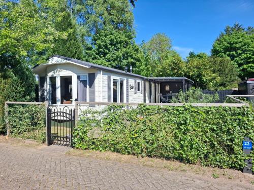 a small white house behind a fence at Chalet Relax in Putten