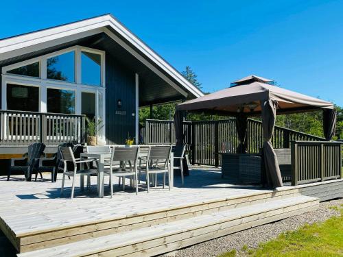 a wooden deck with a table and an umbrella at Modern Cabin With A Short Walk To The Sea in Skjærhollen