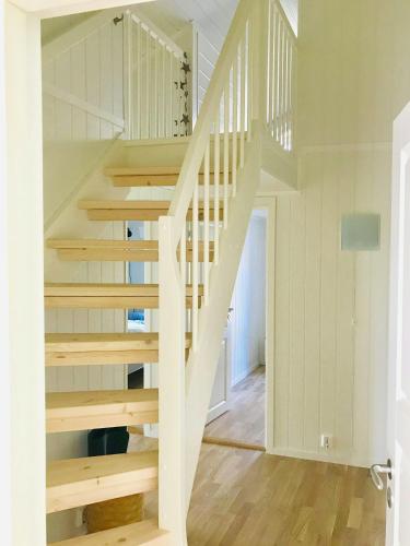 a white staircase in a white room with wooden floors at Modern Cabin With A Short Walk To The Sea in Skjærhollen