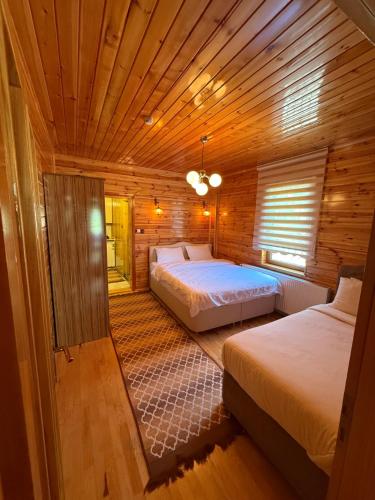 a bedroom with two beds in a wooden cabin at Konçoğlu Pansiyon in Uzungöl