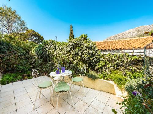 a patio with a table and chairs and a hedge at Dubrovnik Coastal Gem in Dubrovnik