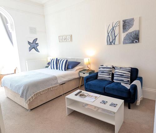 a bedroom with a bed and a couch and a table at Rose Court Holiday Apartments in Torquay