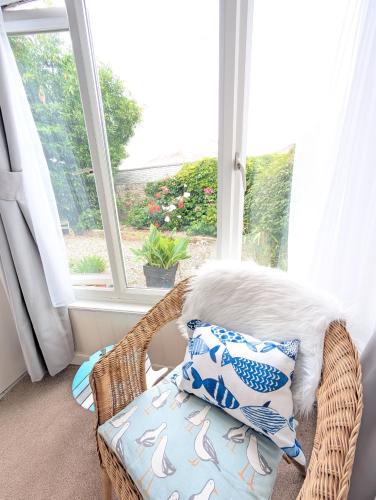 a wicker chair with pillows in front of a window at Rose Court Holiday Apartments in Torquay