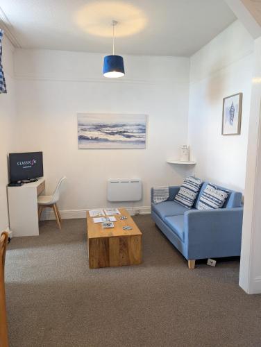 a living room with a blue couch and a coffee table at Rose Court Holiday Apartments in Torquay