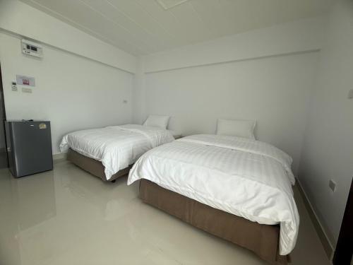 two beds in a room with white walls at ฟินแลนด์ เพลส แอนด์ โฮเทล in Ban Map Samet Daeng