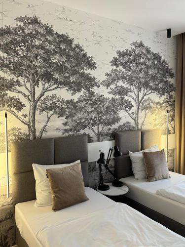 two beds in a room with trees on the wall at Aparthotel Riva in Zawiercie
