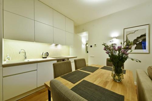 una cucina e un tavolo con un vaso di fiori sopra di Domillion 3bdr 2baths President Palace park L419A a Vilnius