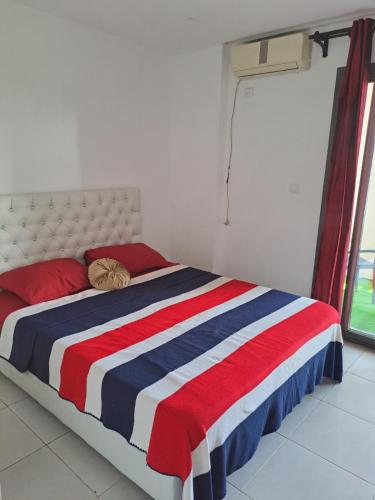 a bed with a red white and blue striped blanket at SaintGermain in Aïn El Turk