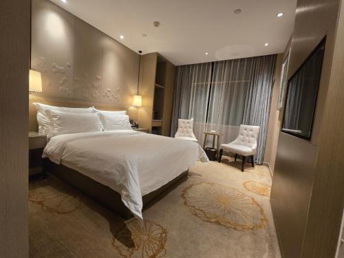 a bedroom with a large bed and a table and chairs at Byland Star Hotel in Yiwu