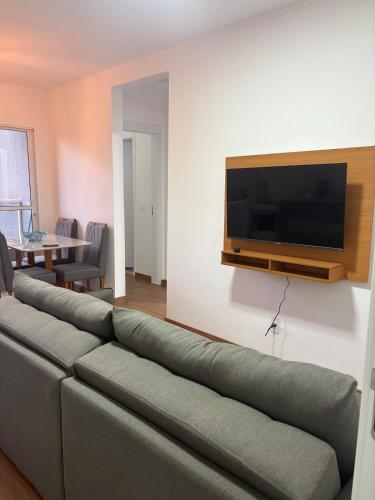 a living room with a couch and a flat screen tv at Apartamento próximo ao Hospital de Amor in Barretos