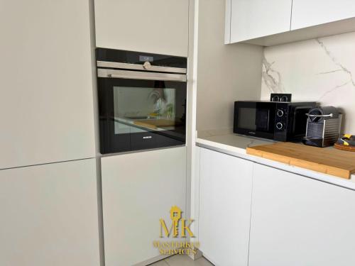 a kitchen with white cabinets and a microwave at T2 Vue Pompidou Balcon, Sport & Centre Muse in Metz