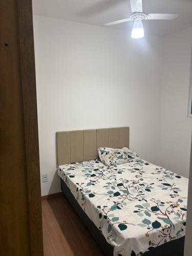 a bedroom with a bed with a flowery comforter at Apartamento próximo ao Hospital de Amor in Barretos